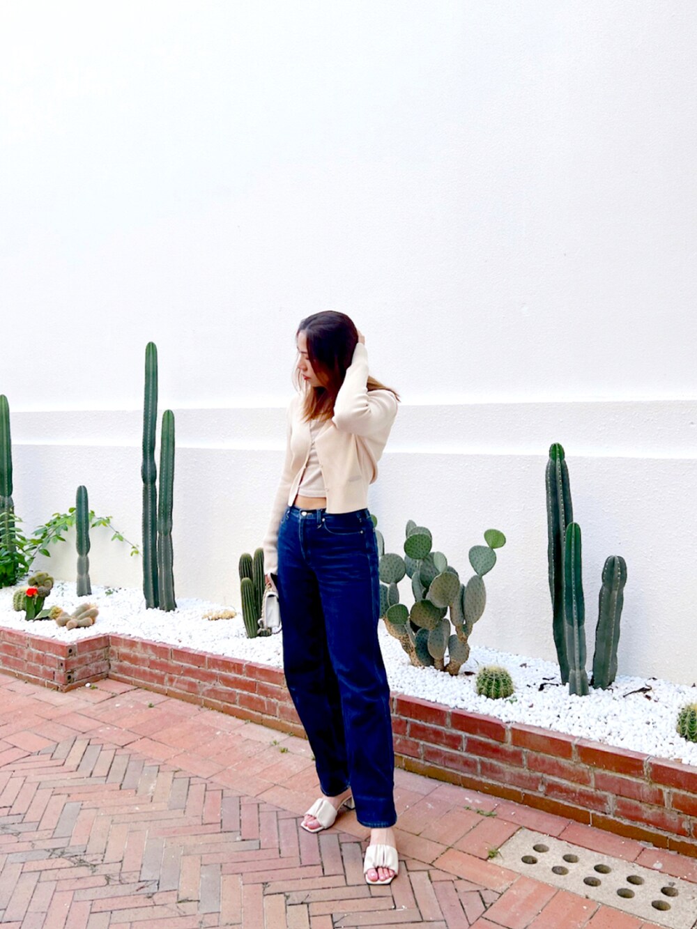 ベージュ系のトップス、ブルー系のデニムパンツ、ベージュ系のサンダルを着用したレディースの秋コーディネートの2枚目の写真