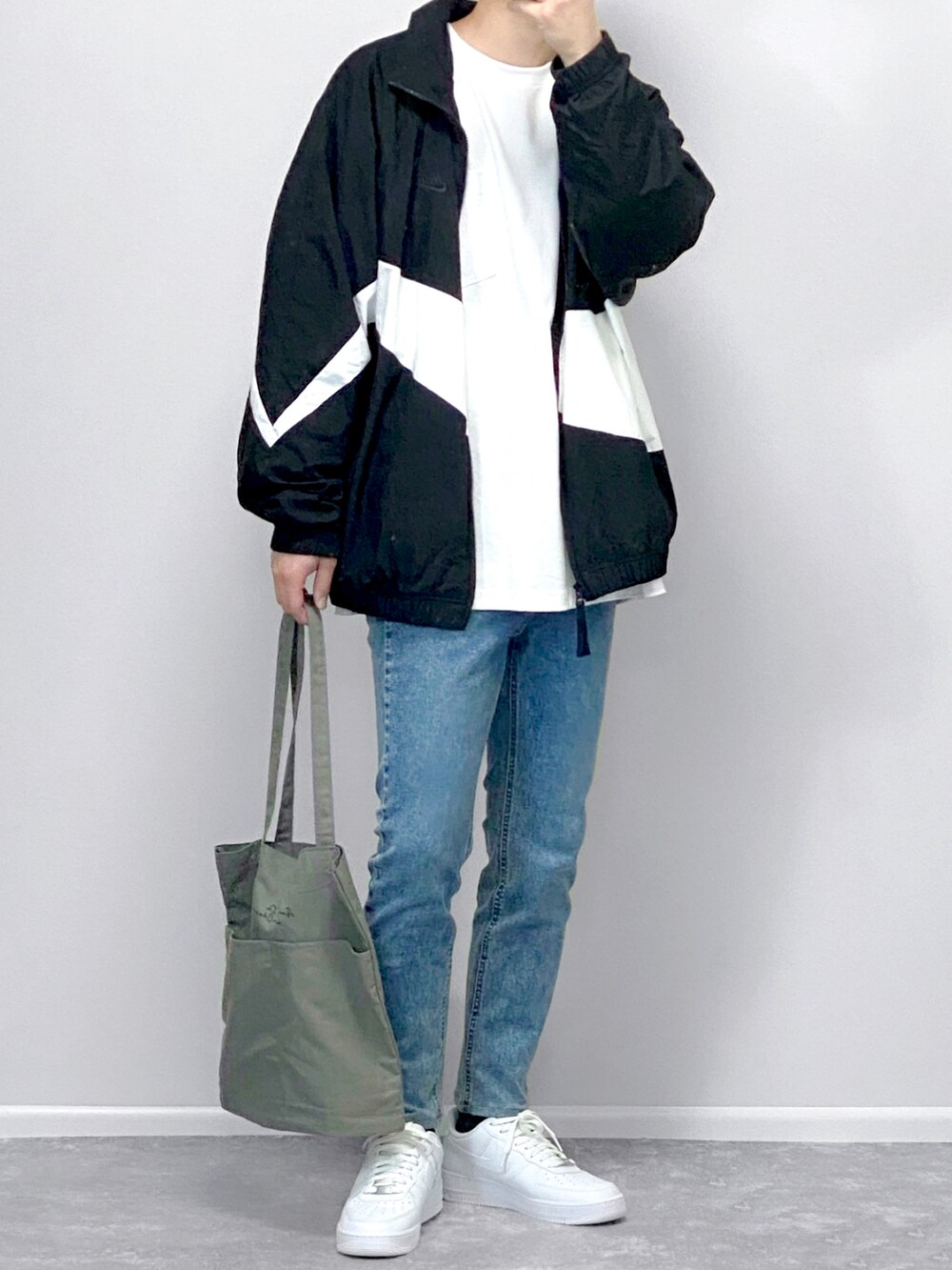 ブラック系のナイロンジャケット、ブラック系のその他パンツ、ホワイト系のスニーカーを着用したメンズの春コーディネートの2枚目の写真