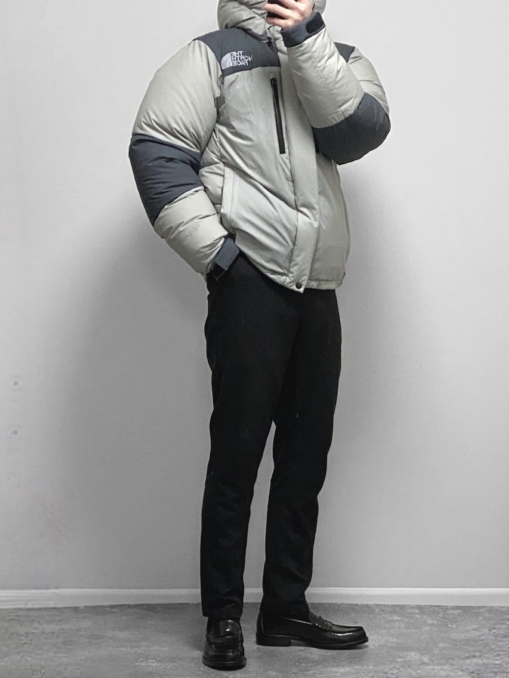 ブルー系のデニムパンツ、ブラック系のダウンジャケット/コート、ブラック系のローファーを着用したメンズの冬コーディネートの2枚目の写真