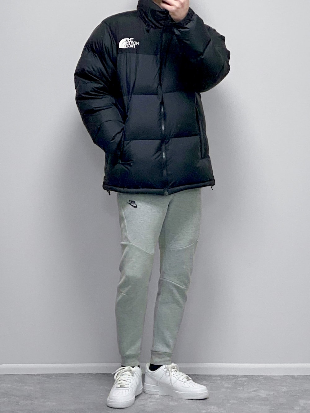 ブラック系のダウンジャケット/コート、ホワイト系のトップス、グレー系のその他パンツを着用したメンズの春コーディネートの2枚目の写真