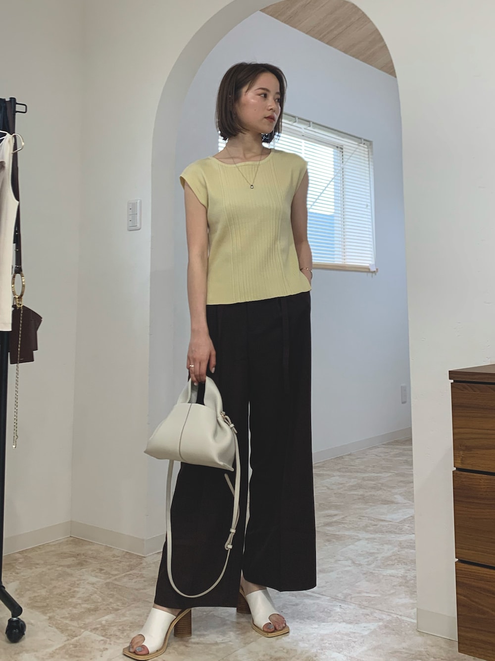 イエロー系のニット/セーター、ブラック系のサンダル、ホワイト系のバッグを着用したレディースの春コーディネートの3枚目の写真