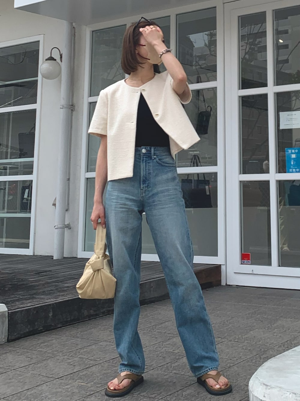 ホワイト系のジャケット/アウター、ブルー系のデニムパンツ、ベージュ系のハンドバッグを着用したレディースの夏コーディネートの2枚目の写真