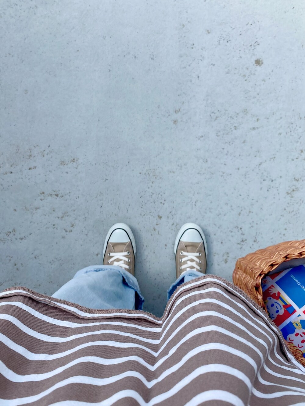 ベージュ系のスニーカー、ブルー系のパンツ、ブラウン系のバッグを着用したレディースの春コーディネートの2枚目の写真