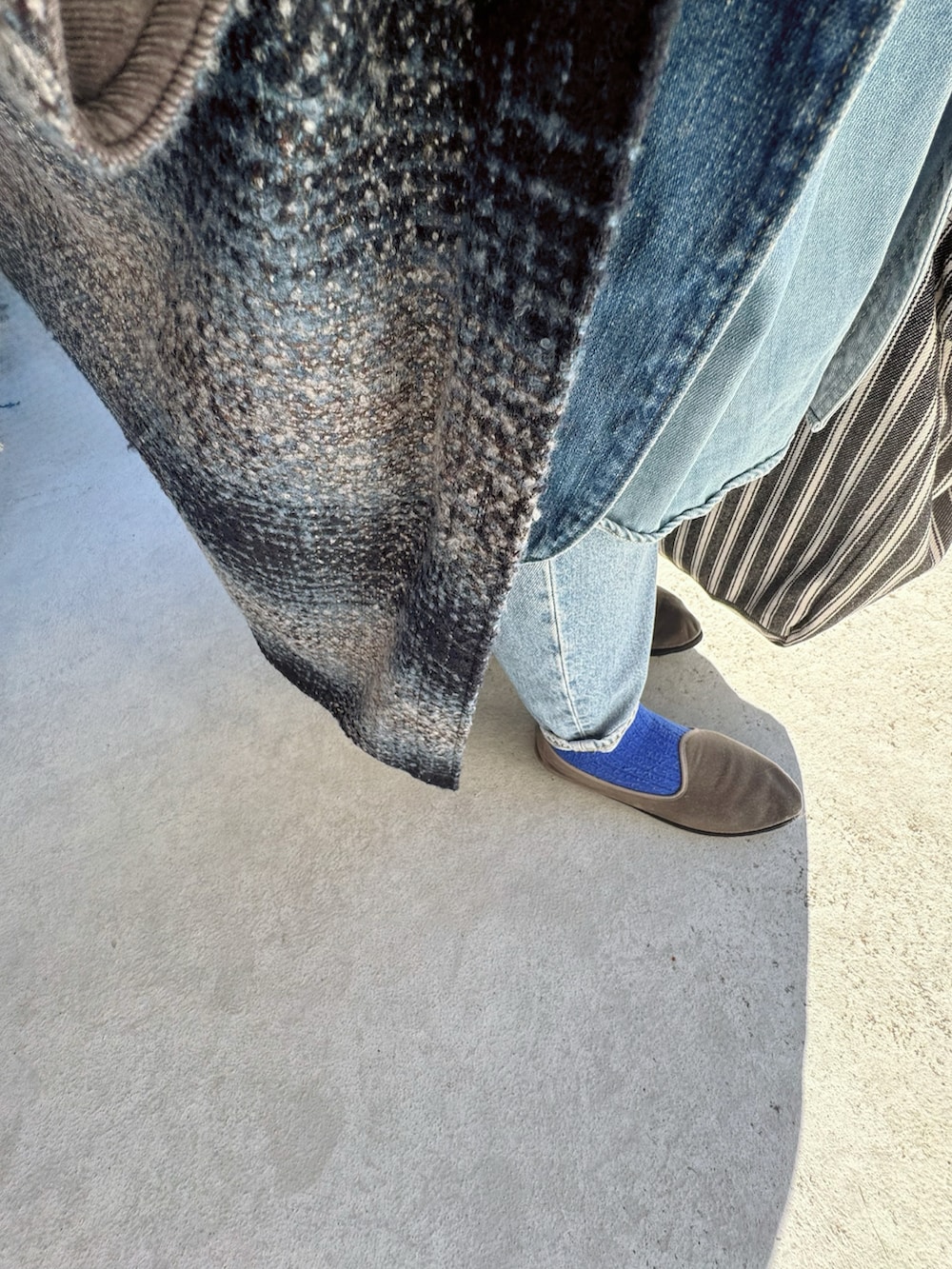 グレー系のスリッポン、ブルー系のパンツ、ブラック系のバッグを着用したレディースの冬コーディネートの2枚目の写真