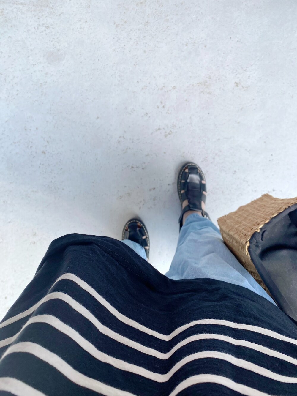 ブラック系のシューズ、ブルー系のデニムパンツ、ベージュ系のバッグを着用したレディースの夏コーディネートの2枚目の写真