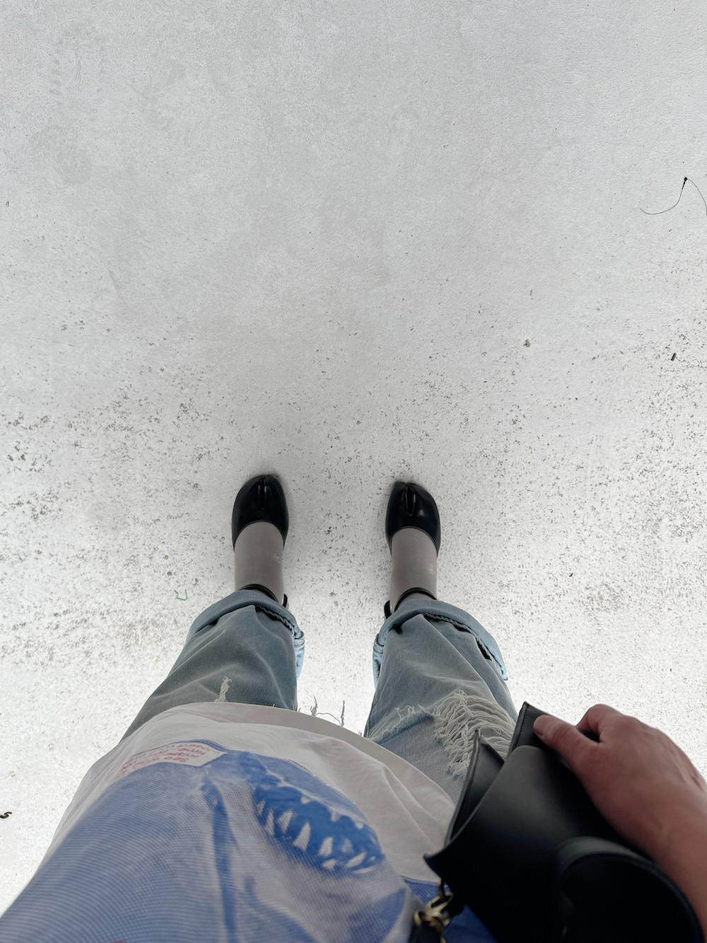 ブラック系のパンプス、ブルー系のパンツ、ブラック系のハンドバッグを着用したレディースの夏コーディネートの2枚目の写真