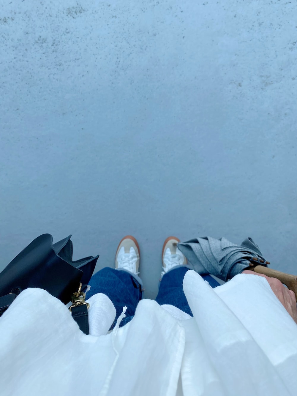 ホワイト系のスニーカー、ブルー系のパンツ、ブラック系のショルダーバッグを着用したレディースの夏コーディネートの3枚目の写真