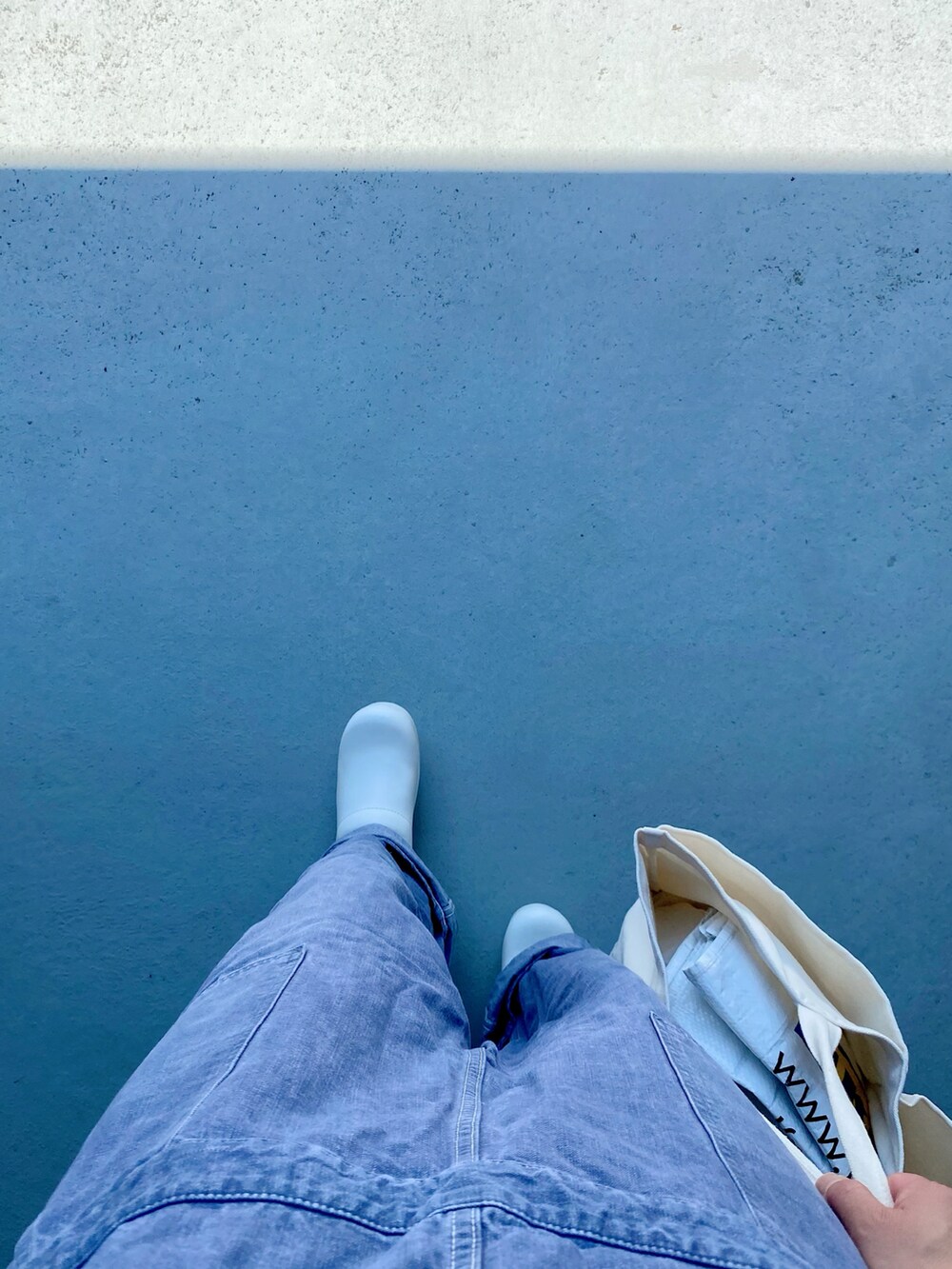 ブラック系のサンダル、ブルー系のオールインワン・サロペット、ホワイト系のバッグを着用したレディースの夏コーディネートの2枚目の写真