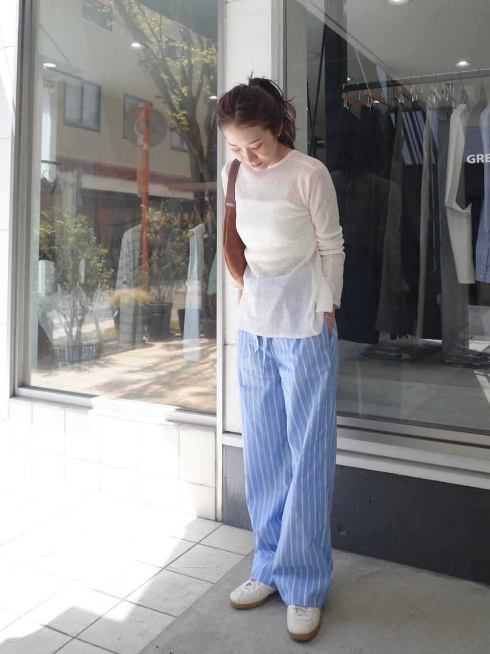 ブルー系のその他パンツ、ホワイト系のニット/セーター、ホワイト系のスニーカーを着用したレディースの春コーディネートの2枚目の写真