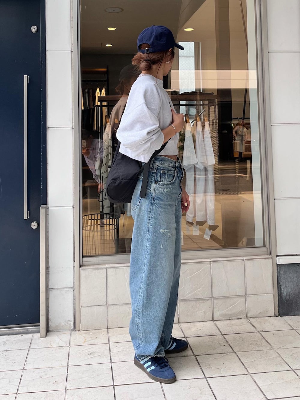 ブルー系のデニムパンツ、ブルー系のスニーカー、グレー系のスウェットを着用したレディースの春コーディネートの2枚目の写真