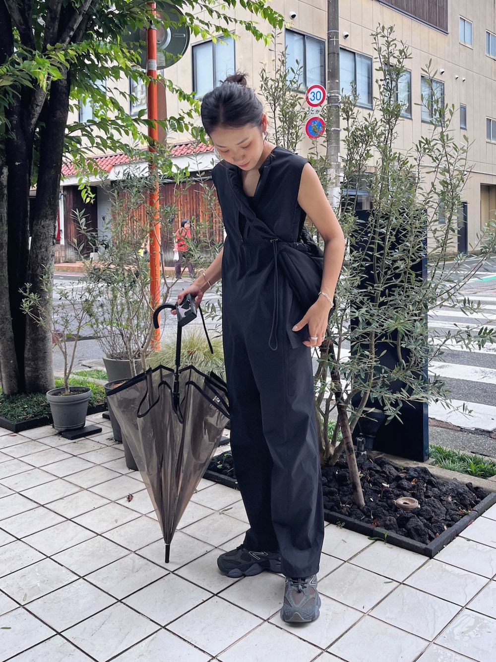 ブラック系のショルダーバッグ、ブラウン系のスニーカー、ブラック系のラッシュガードを着用したレディースの夏コーディネートの2枚目の写真