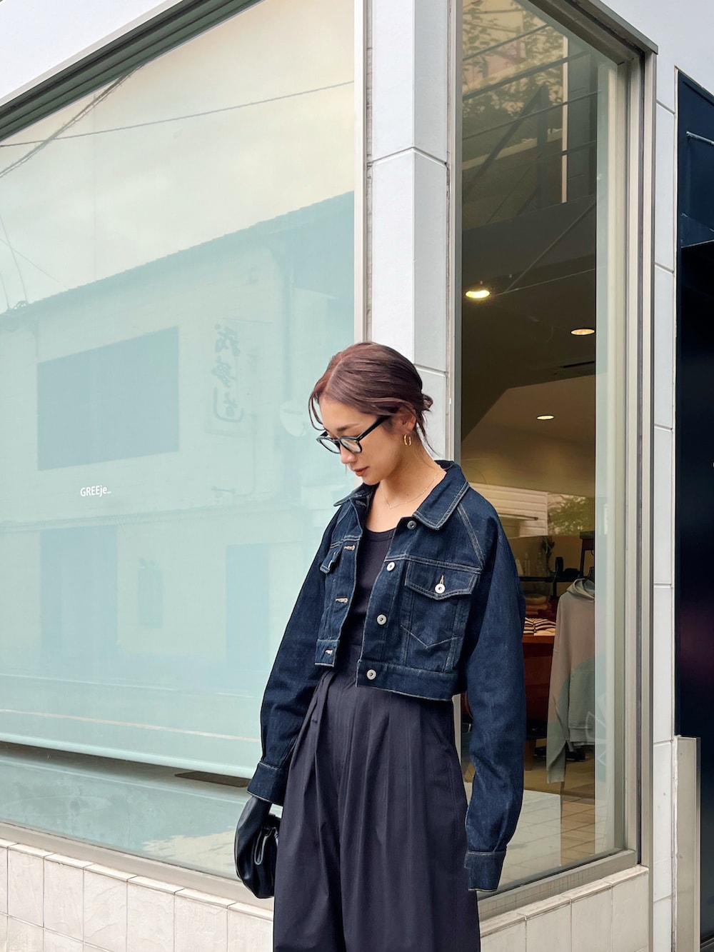 ブルー系のデニムジャケット、ブラック系のその他パンツ、ホワイト系のスニーカーを着用したレディースの秋コーディネートの2枚目の写真