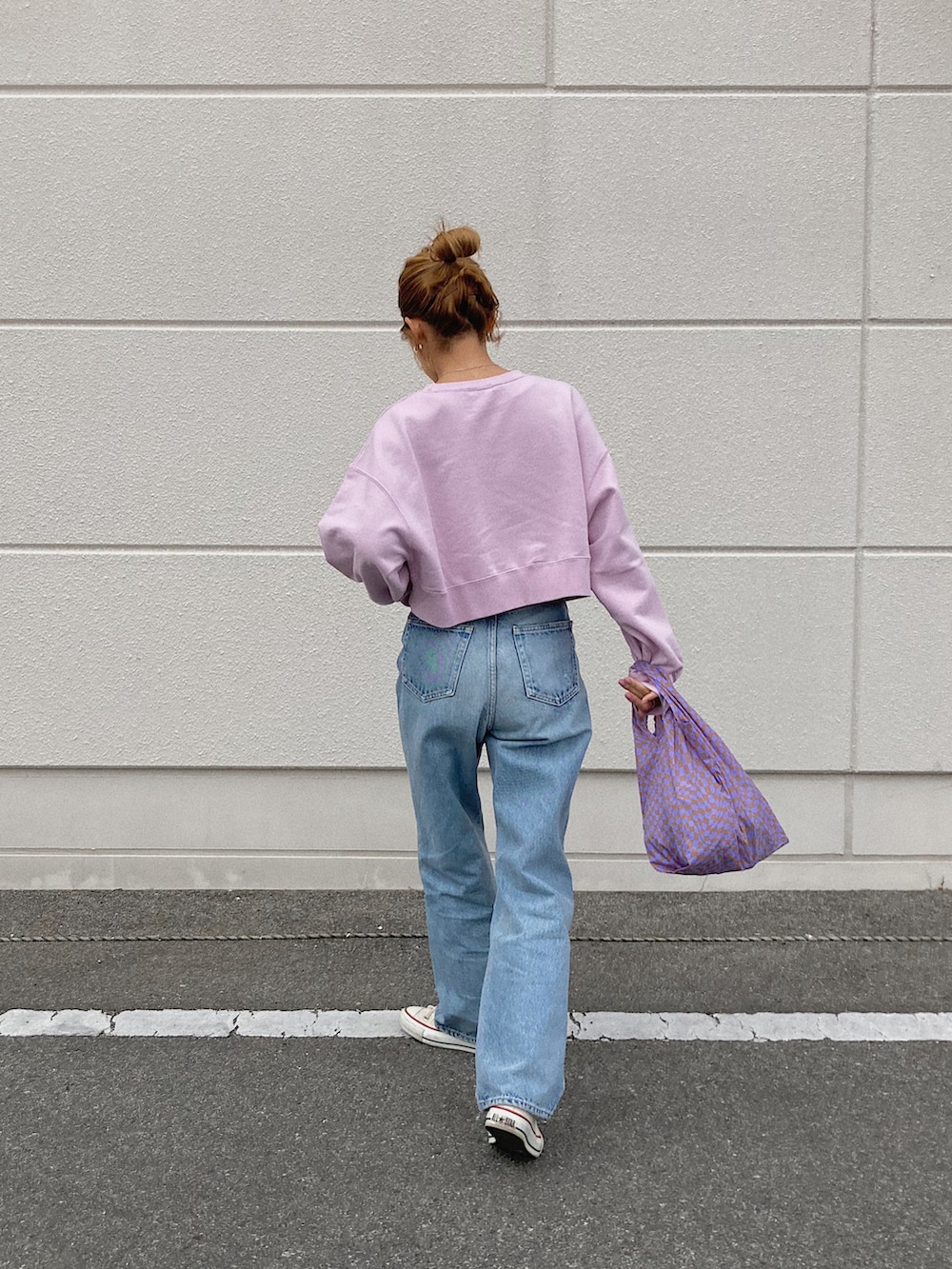 ピンク系のスウェット、ブルー系のデニムパンツ、ホワイト系のスニーカーを着用したレディースの春コーディネートの2枚目の写真