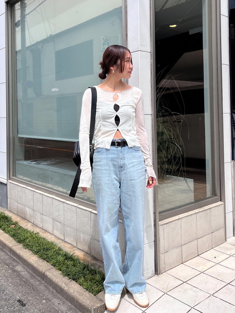 ブルー系のデニムパンツ、ベージュ系のTシャツ/カットソー、ホワイト系のスニーカーを着用したレディースの春コーディネートの2枚目の写真