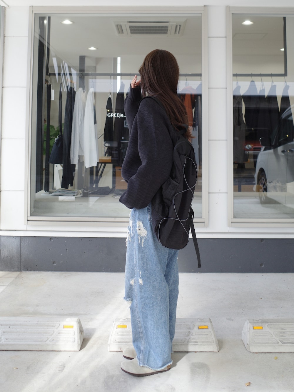 ブルー系のデニムパンツ、ブラック系のバックパック/リュック、ブラック系のニット/セーターを着用したレディースの秋コーディネートの2枚目の写真