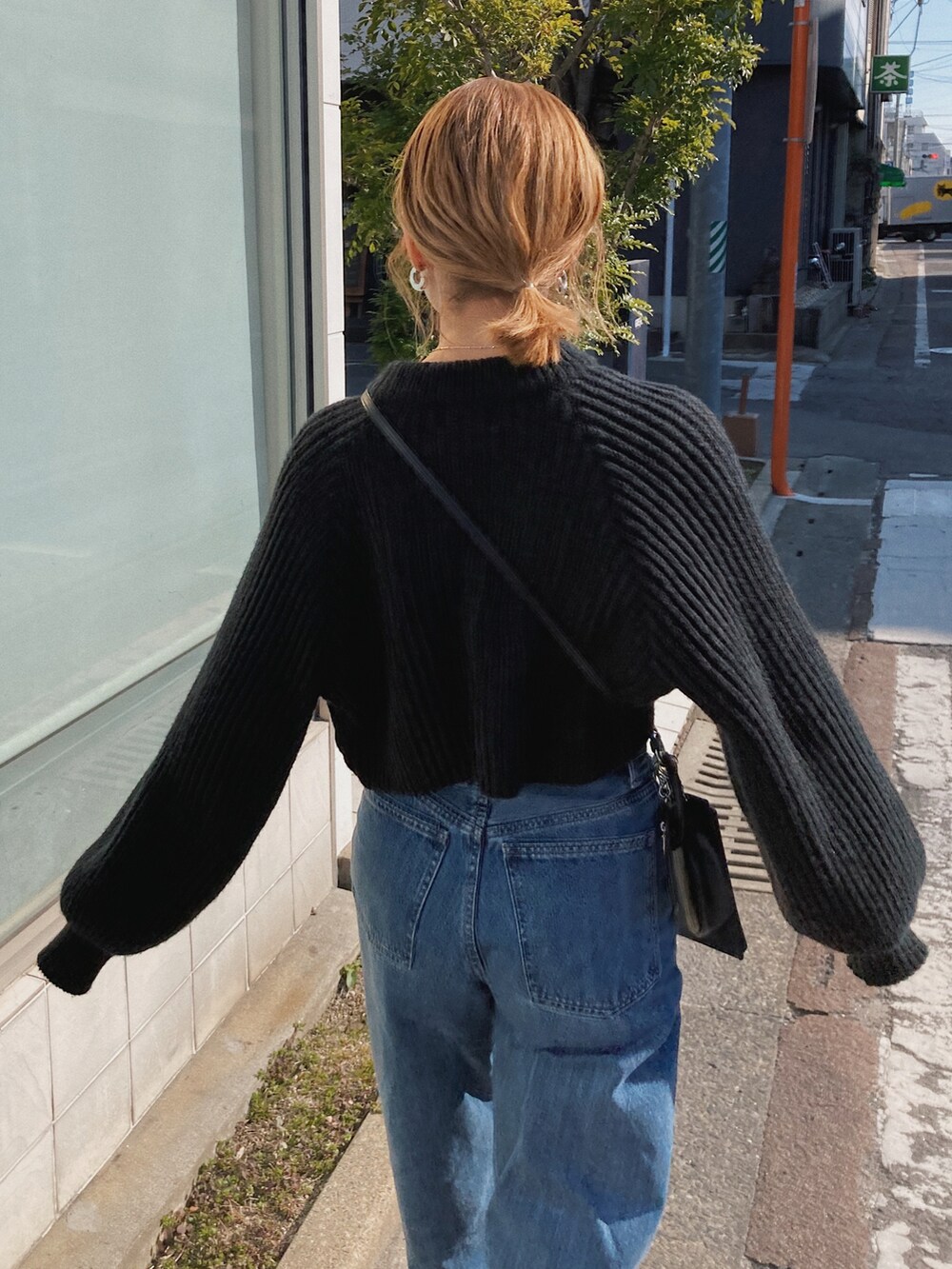 ブラック系のニット/セーター、ブルー系のデニムパンツ、ブラック系のブーツを着用したレディースの冬コーディネートの2枚目の写真