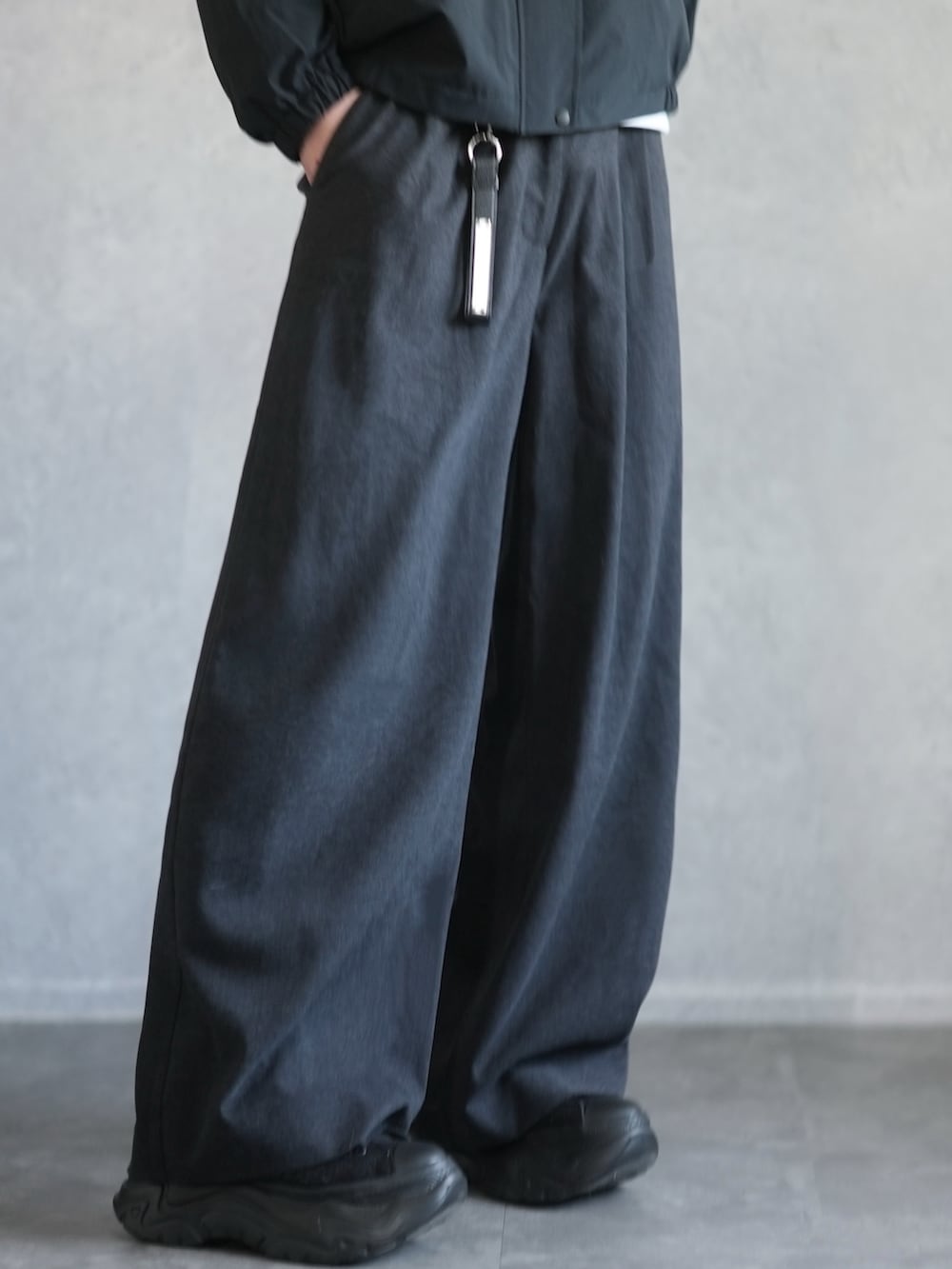 グレー系のスラックス、ブラック系のスニーカー、ホワイト系のスウェットを着用したメンズの冬コーディネートの3枚目の写真