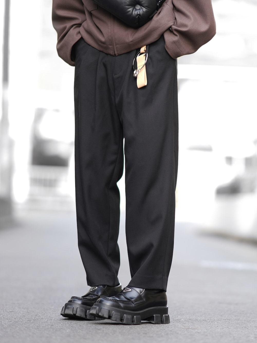 ブラウン系のブルゾン、ブラック系のニット/セーター、ブラック系のスラックスを着用したメンズの冬コーディネートの3枚目の写真