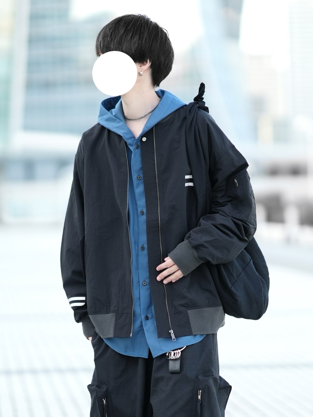 ブラック系のブルゾン、ブルー系のパーカー、ブラック系のカーゴパンツを着用したメンズの冬コーディネートの2枚目の写真