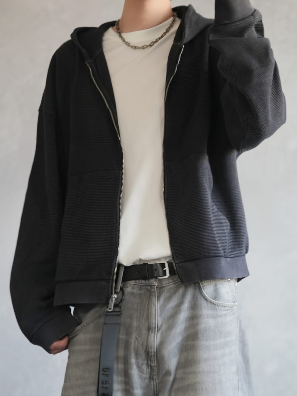 ブラック系のパーカー、ホワイト系のタンクトップ、グレー系のデニムパンツを着用したメンズの春コーディネートの2枚目の写真