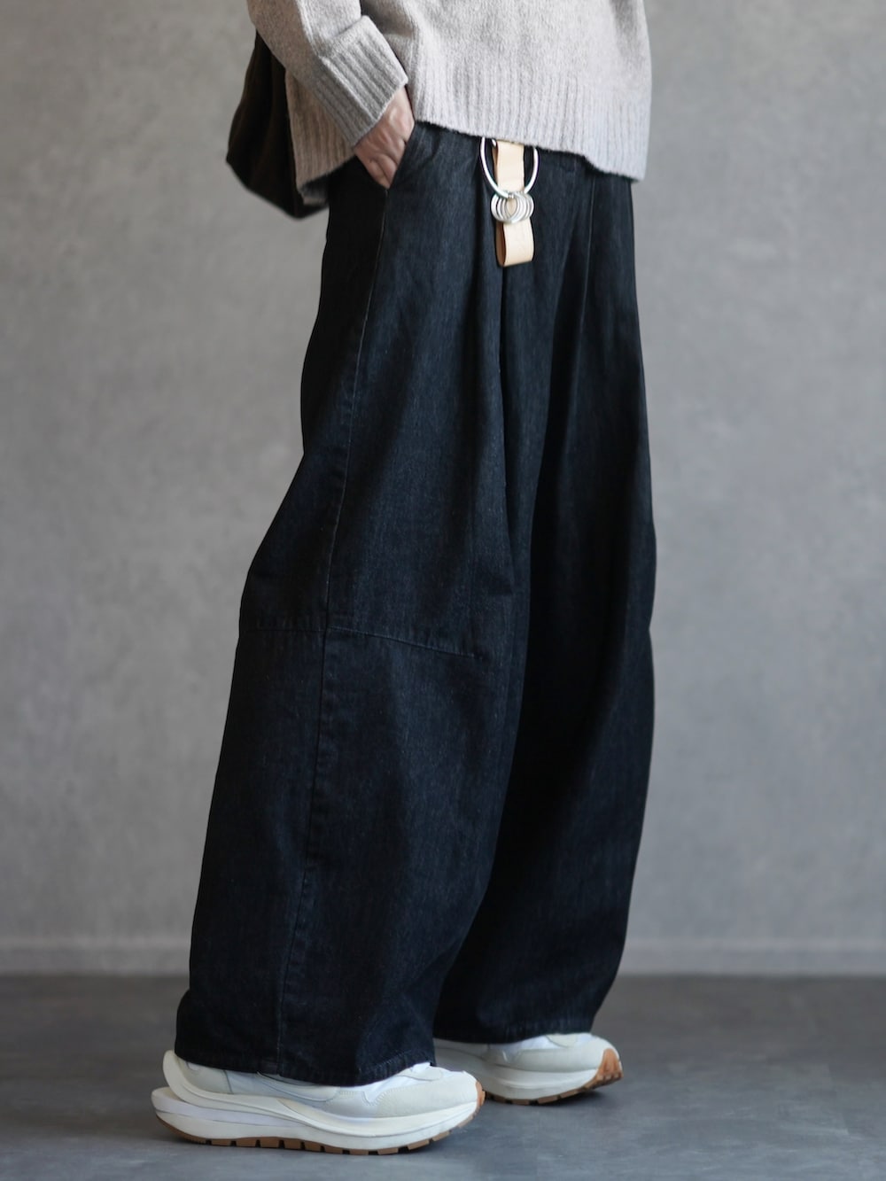 ベージュ系のニット/セーター、ブラック系のデニムパンツ、ホワイト系のスニーカーを着用したメンズの秋コーディネートの3枚目の写真