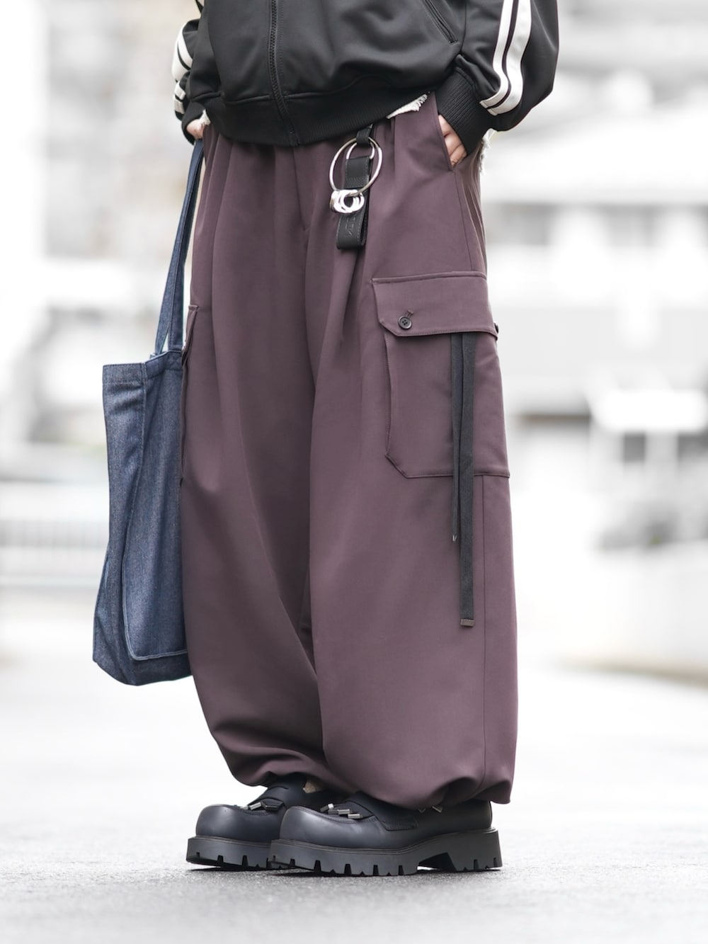 ブラック系のジャージ、ブルー系のトートバッグ、ブラウン系のカーゴパンツを着用したメンズの冬コーディネートの3枚目の写真