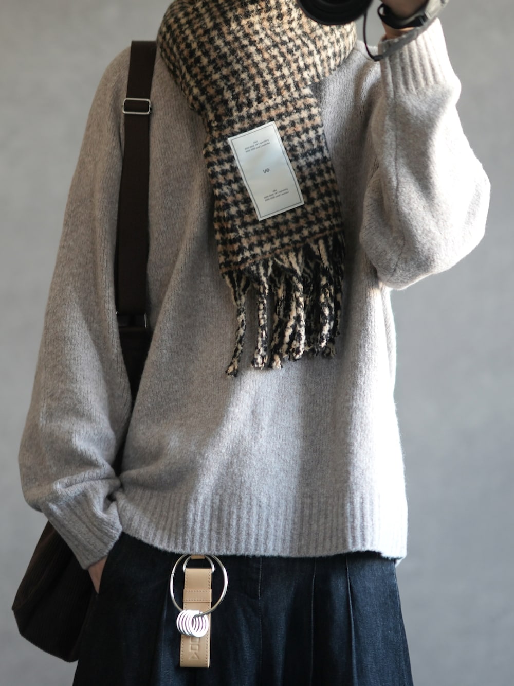 ベージュ系のニット/セーター、ブラック系のデニムパンツ、ホワイト系のスニーカーを着用したメンズの秋コーディネートの2枚目の写真