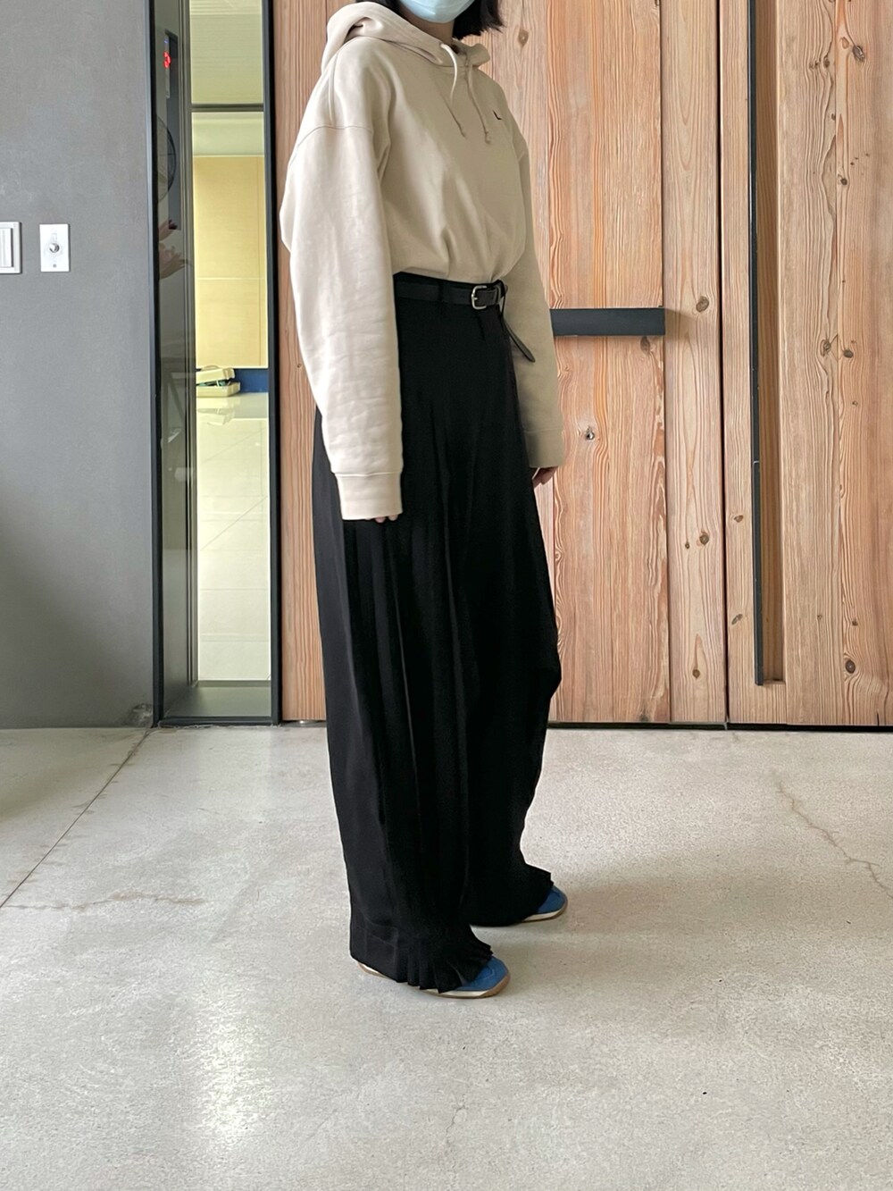 ブラック系のスラックス、ベージュ系のパーカー、ブルー系のスニーカーを着用したレディースの春コーディネートの2枚目の写真