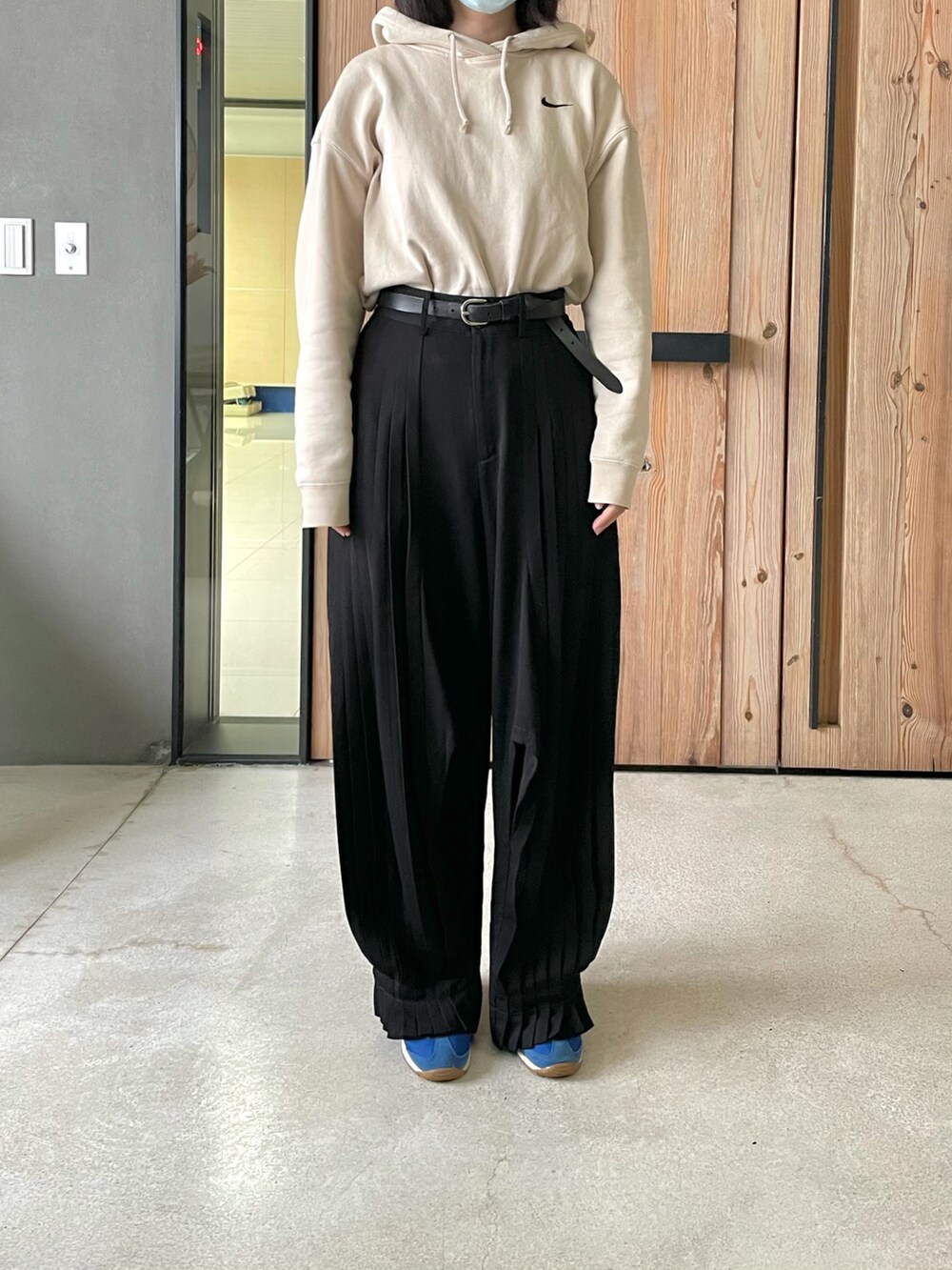 ブラック系のスラックス、ベージュ系のパーカー、ブルー系のスニーカーを着用したレディースの春コーディネートの3枚目の写真