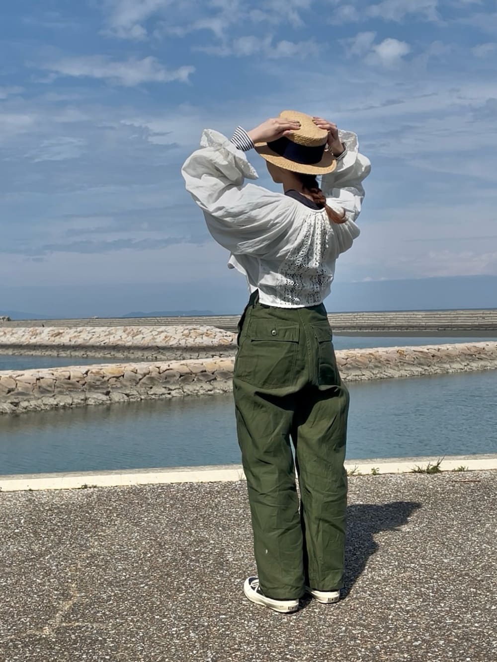 グレー系のトップス、グリーン系のパンツ、ブラック系のスニーカーを着用したレディースの春コーディネートの3枚目の写真