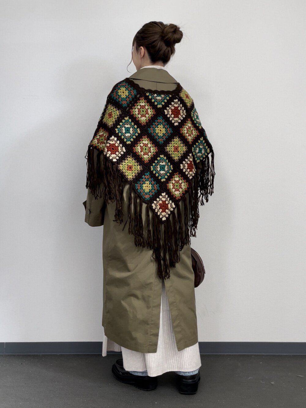 ブラウン系のポンチョ、グリーン系のジャケット/アウター、ブラウン系のボストンバッグを着用したレディースの冬コーディネートの3枚目の写真