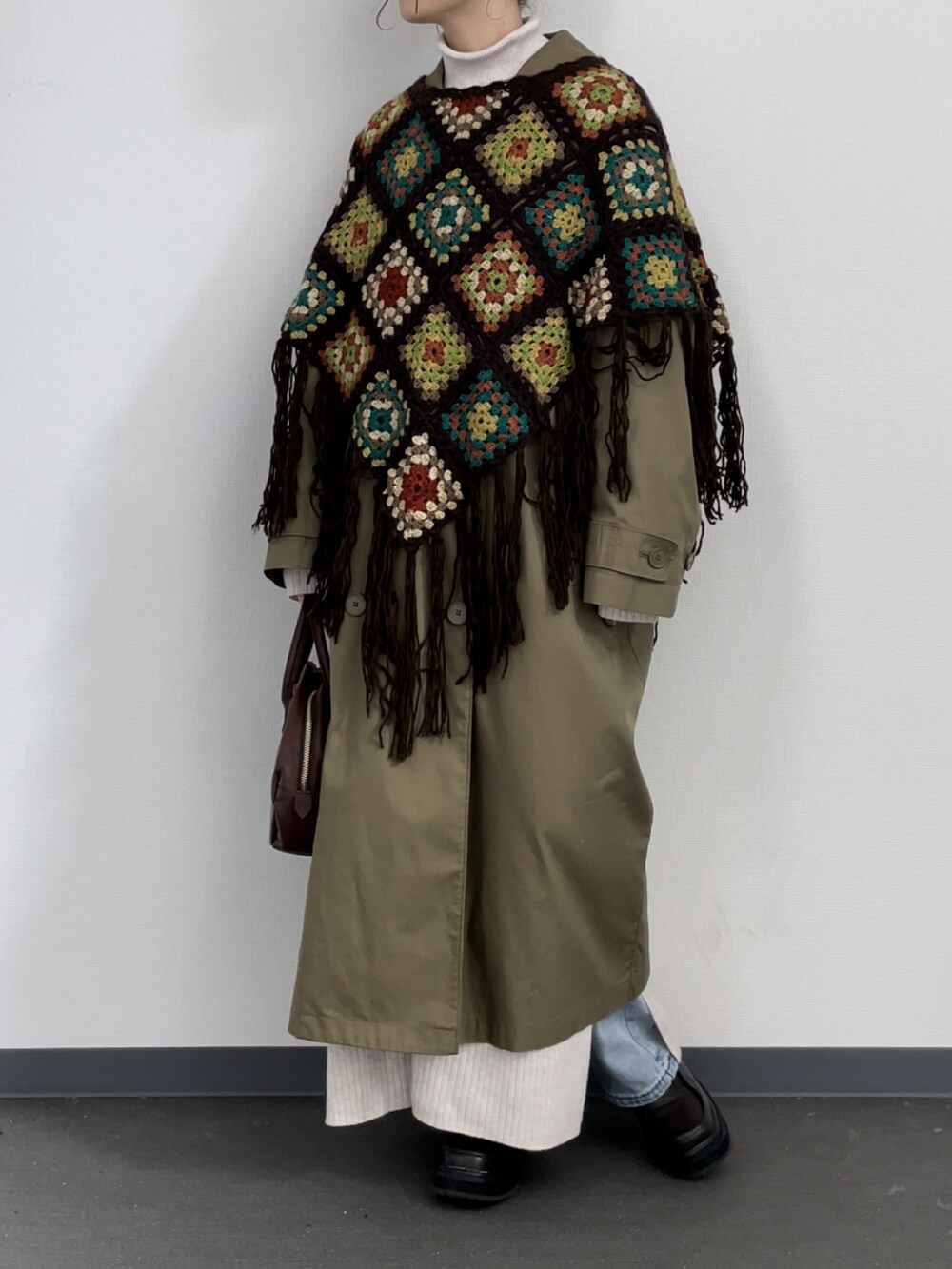 ブラウン系のポンチョ、グリーン系のジャケット/アウター、ブラウン系のボストンバッグを着用したレディースの冬コーディネートの2枚目の写真