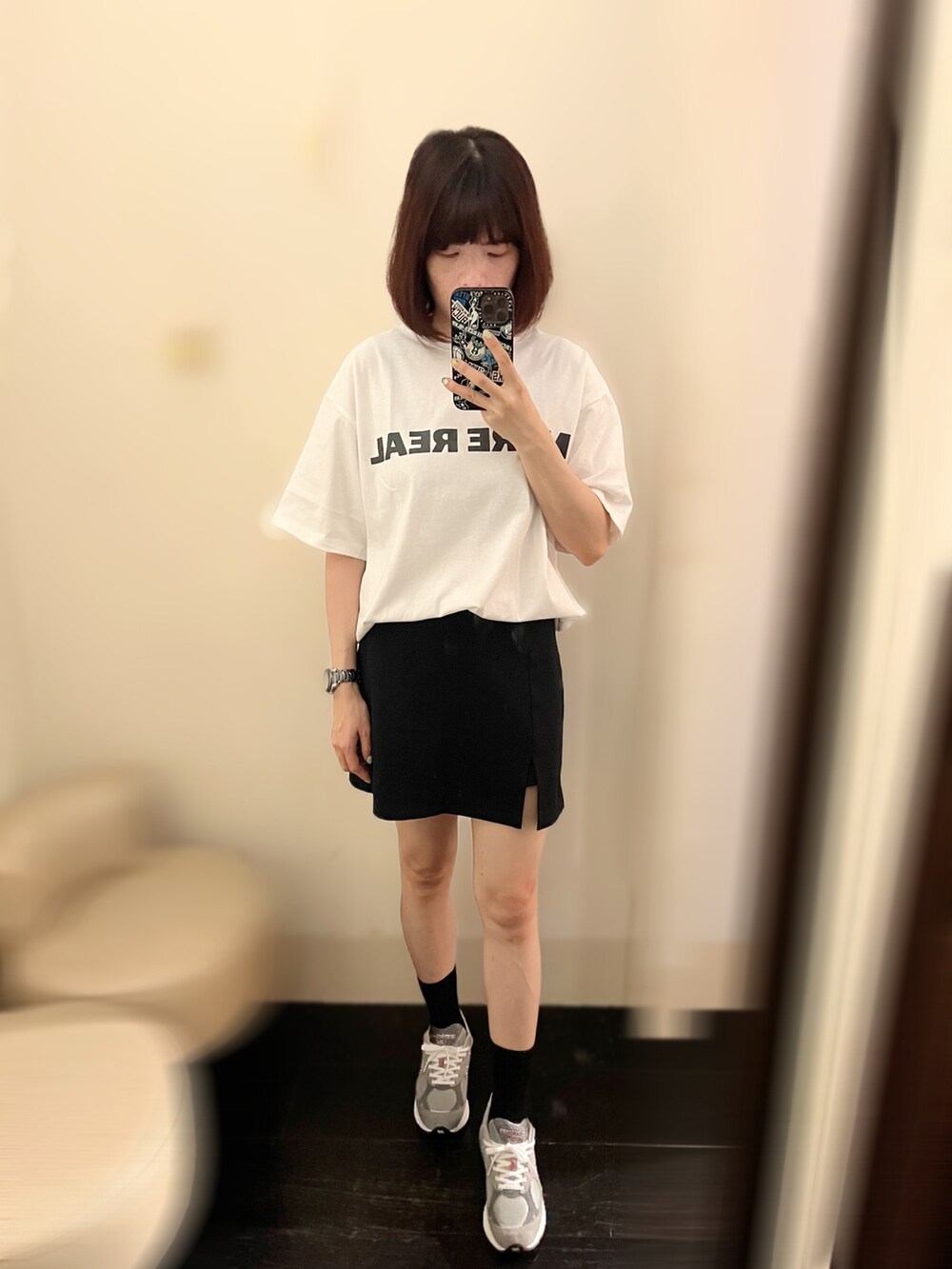 ホワイト系のTシャツ/カットソー、ブラック系のスカート、グレー系のスニーカーを着用したレディースの夏コーディネートの2枚目の写真