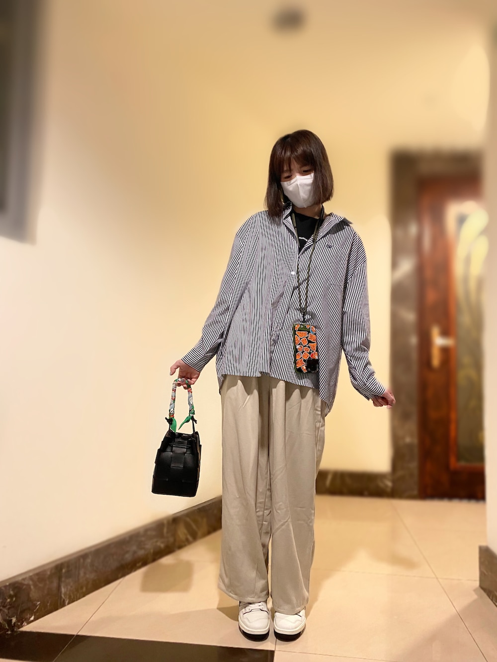 ブルー系のシャツ/ブラウス、ベージュ系のパンツ、ホワイト系のスニーカーを着用したレディースの秋コーディネートの2枚目の写真