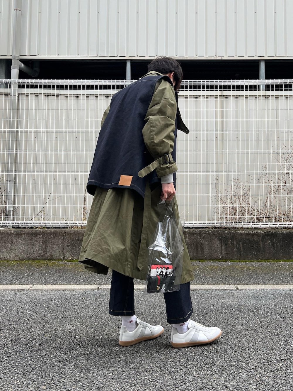「春服みてみて、デニムパンツ、ミリタリー、ミリタリーコーデ、デニムベスト、デニムスラックス、ジャーマントレーナー、レイヤードスタイル、クリアバッグ、PVC、RYOTAKASHIMA、ennoy、カーキアウター、ベスト、ロングコート」｜「Maison Margielaの＜MAISON MARGIELA（メゾン マルジェラ）＞ REPLICA LOW■■■（スニーカー、ホワイト系）」を使った、natsukiさん（メンズ・187cm）の春コーディネートの4枚目の写真