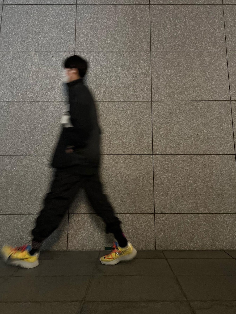 イエロー系のスニーカー、ブラック系のパンツ、ブラック系のナイロンジャケットを着用したメンズの夏コーディネートの2枚目の写真