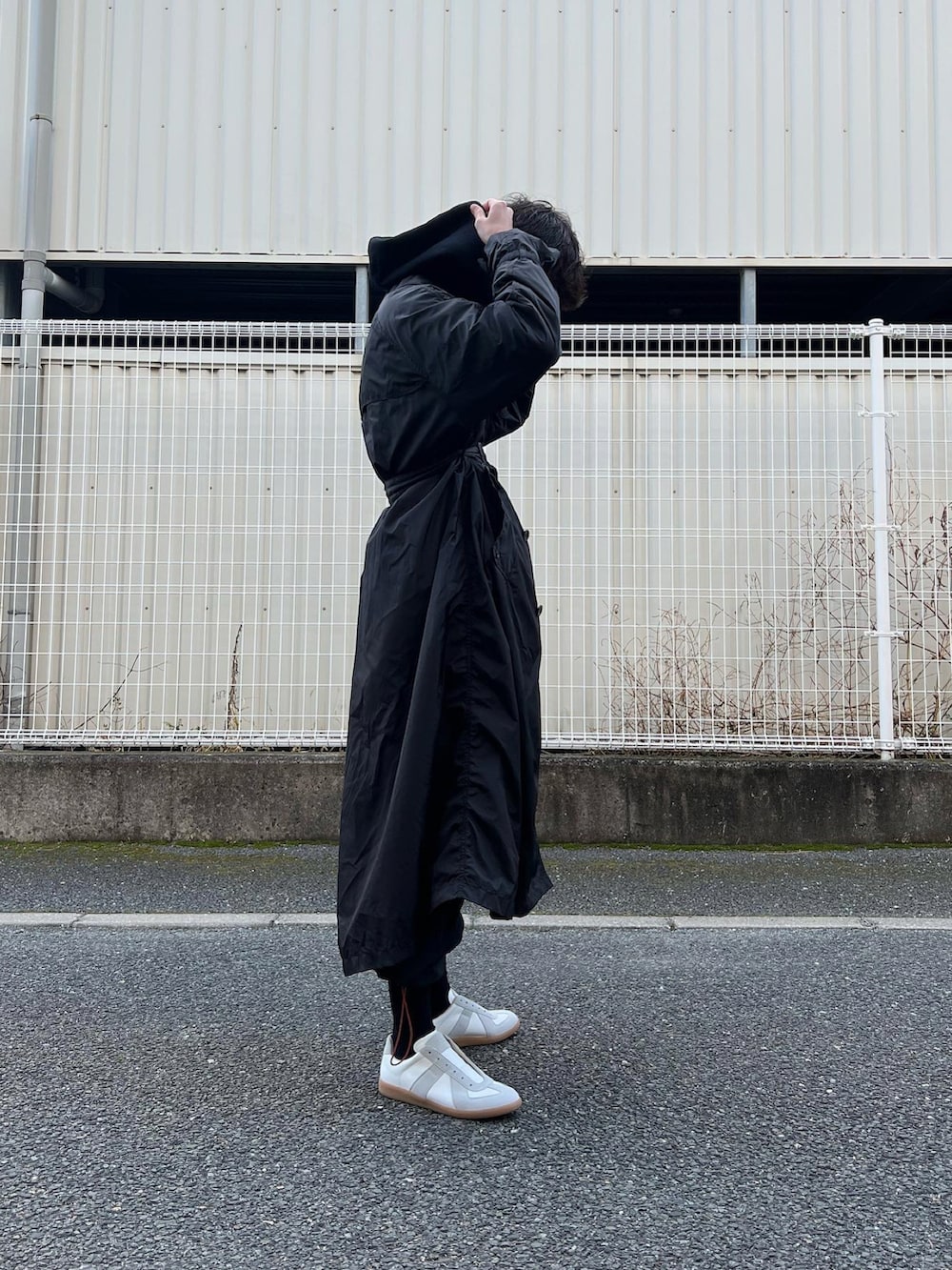 ホワイト系のスニーカー、ブラック系のその他パンツ、ブラック系のトレンチコートを着用したメンズの冬コーディネートの4枚目の写真