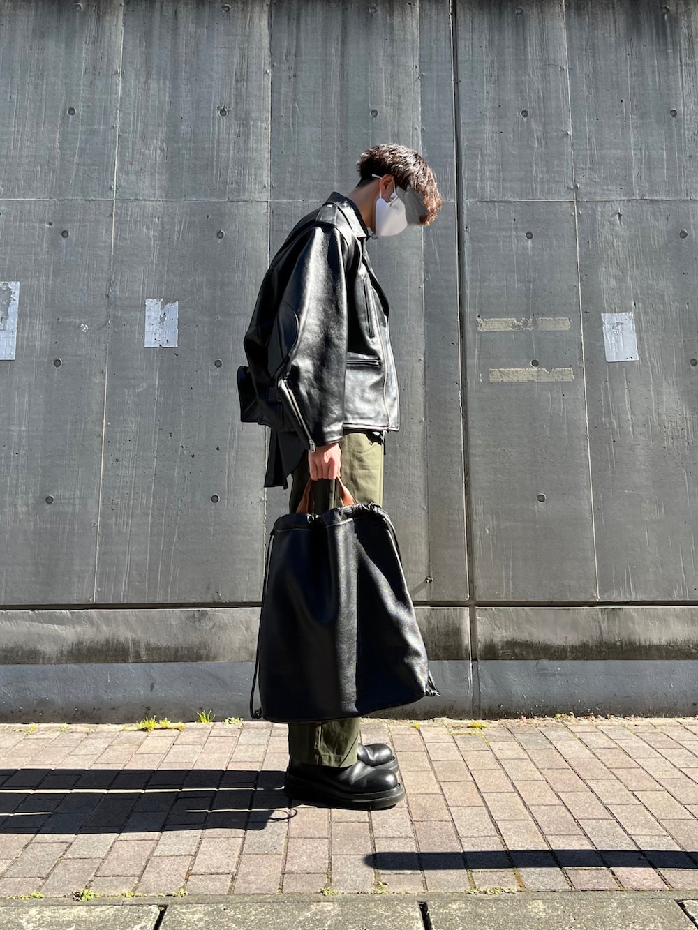 ブラック系のブーツ、ブラック系のトートバッグ、グリーン系のチノパンツを着用したメンズの冬コーディネートの3枚目の写真