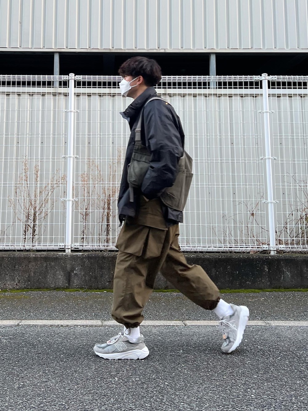 グレー系のスニーカー、グリーン系のその他パンツ、ブラック系のマウンテンパーカーを着用したメンズの冬コーディネートの3枚目の写真