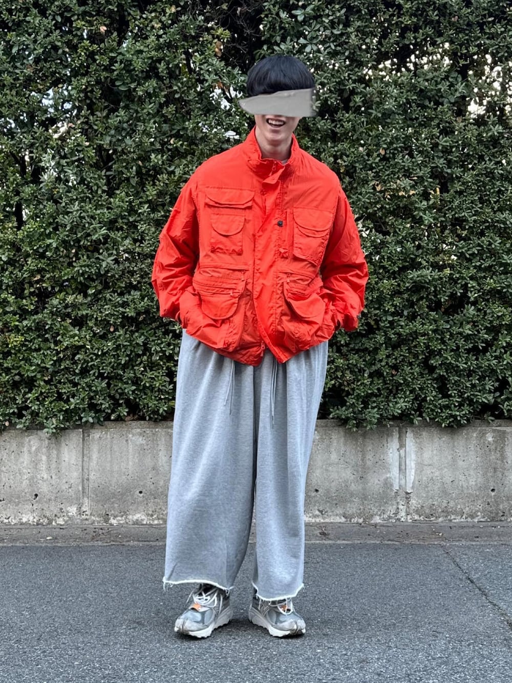 グレー系のスニーカー、グレー系のスウェットパンツ、オレンジ系のナイロンジャケットを着用したメンズの春コーディネートの3枚目の写真