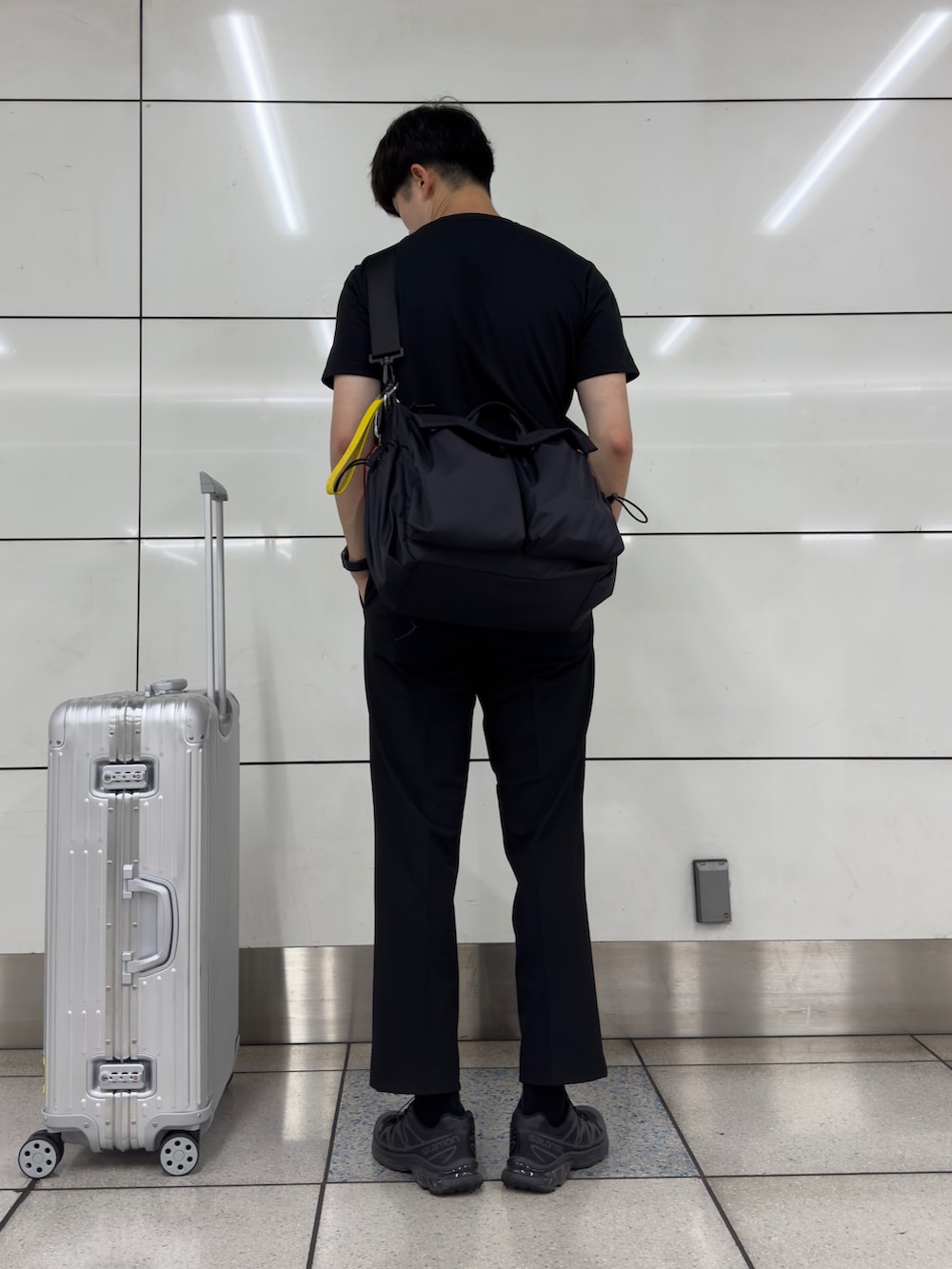 ブラック系のスニーカー、ブラック系のスラックス、シルバー系のスーツケース/キャリーバッグを着用したメンズの秋コーディネートの4枚目の写真