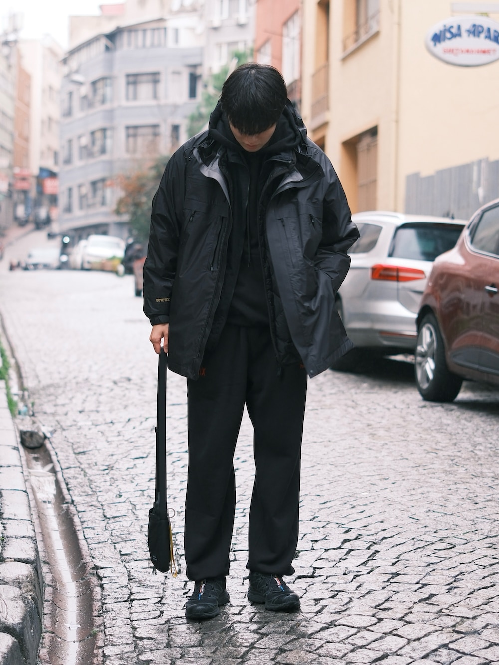 ブラック系のスニーカー、ブラック系のスウェットパンツ、ブラック系のマウンテンパーカーを着用したメンズの冬コーディネートの3枚目の写真