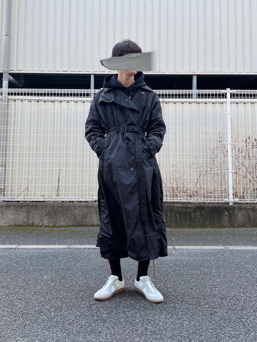 ホワイト系のスニーカー、ブラック系のその他パンツ、ブラック系のトレンチコートを着用したメンズの冬コーディネートの2枚目の写真