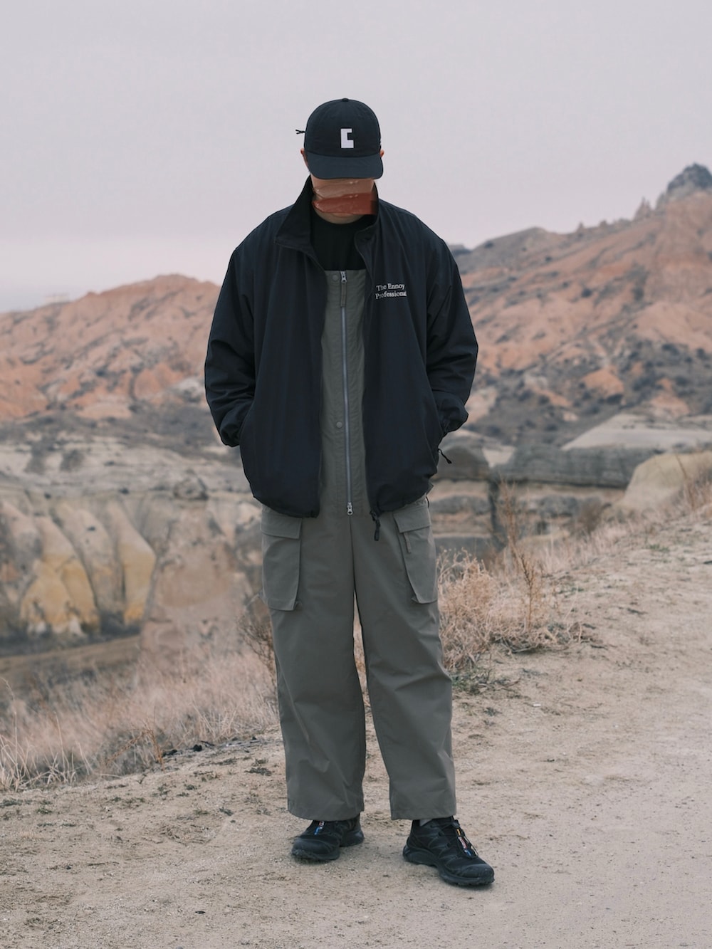 ブラック系のナイロンジャケット、グリーン系のサロペット/オーバーオール、ブラック系のスニーカーを着用したメンズの冬コーディネートの2枚目の写真