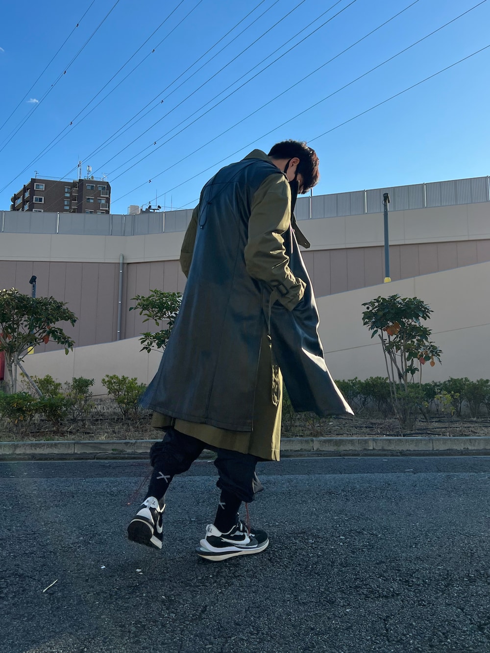 ブラック系のスニーカー、ブラック系のパンツ、ブラック系のベストを着用したメンズの冬コーディネートの3枚目の写真