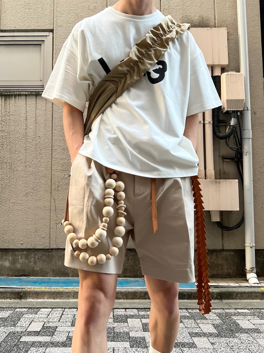 ホワイト系のスニーカー、ベージュ系のその他パンツ、ベージュ系のショルダーバッグを着用したメンズの夏コーディネートの5枚目の写真