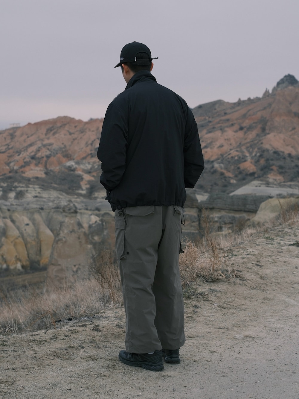 ブラック系のナイロンジャケット、グリーン系のサロペット/オーバーオール、ブラック系のスニーカーを着用したメンズの冬コーディネートの5枚目の写真