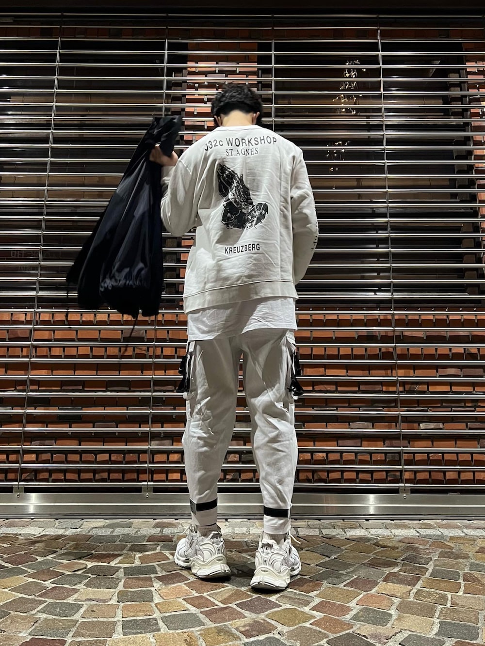 ホワイト系のスニーカー、ホワイト系のカーゴパンツ、ブラック系のナイロンジャケットを着用したメンズの冬コーディネートの3枚目の写真