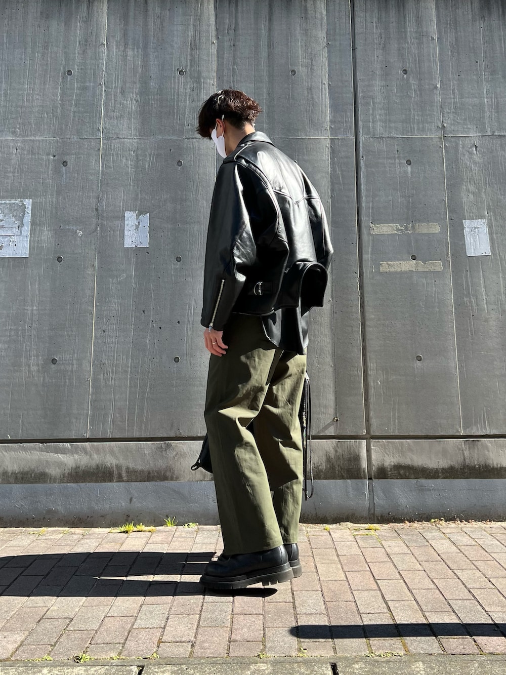 ブラック系のブーツ、ブラック系のトートバッグ、グリーン系のチノパンツを着用したメンズの冬コーディネートの4枚目の写真