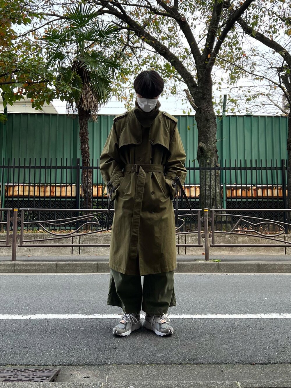 グレー系のスニーカー、グリーン系のカーゴパンツ、グリーン系のトレンチコートを着用したメンズの冬コーディネートの4枚目の写真